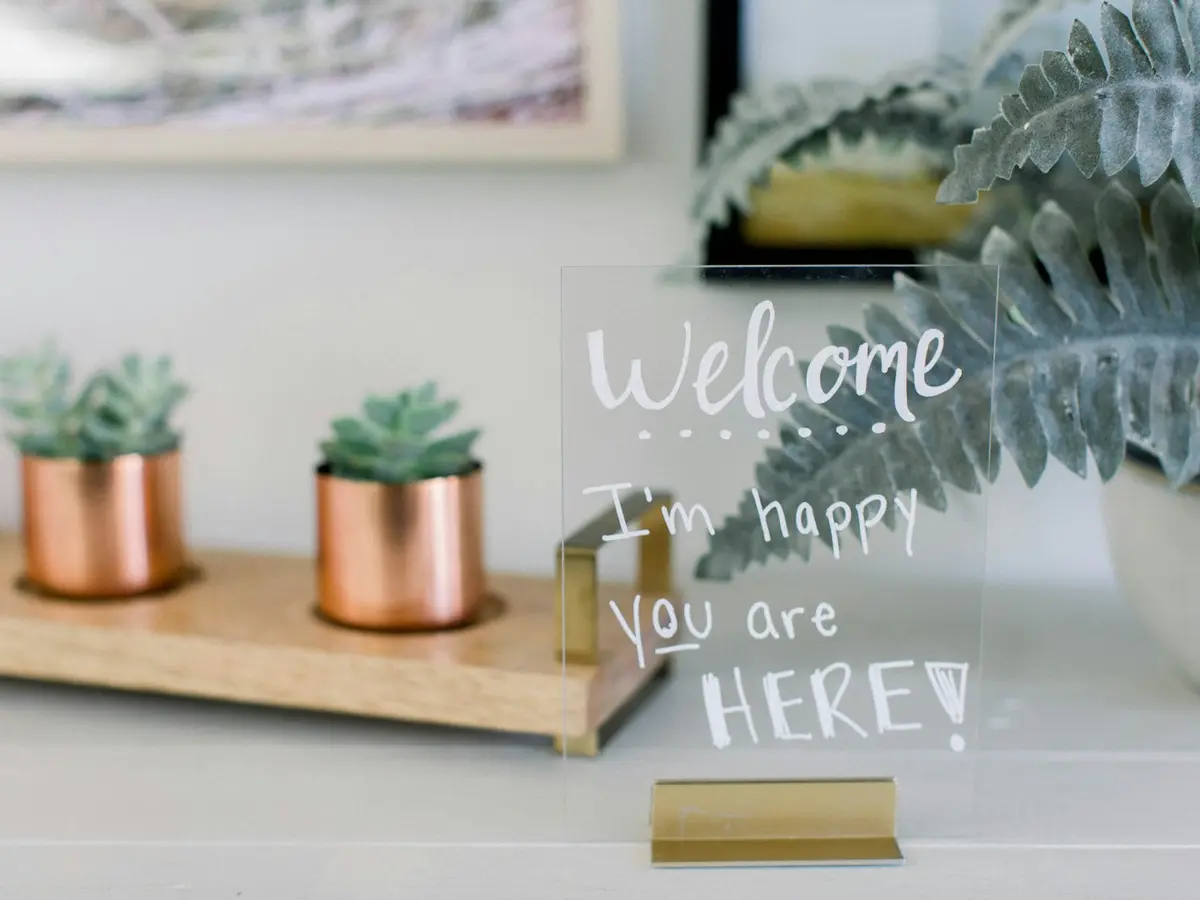 Display de mesa em acrílico transparente com mensagem de boas-vindas e base dourada
