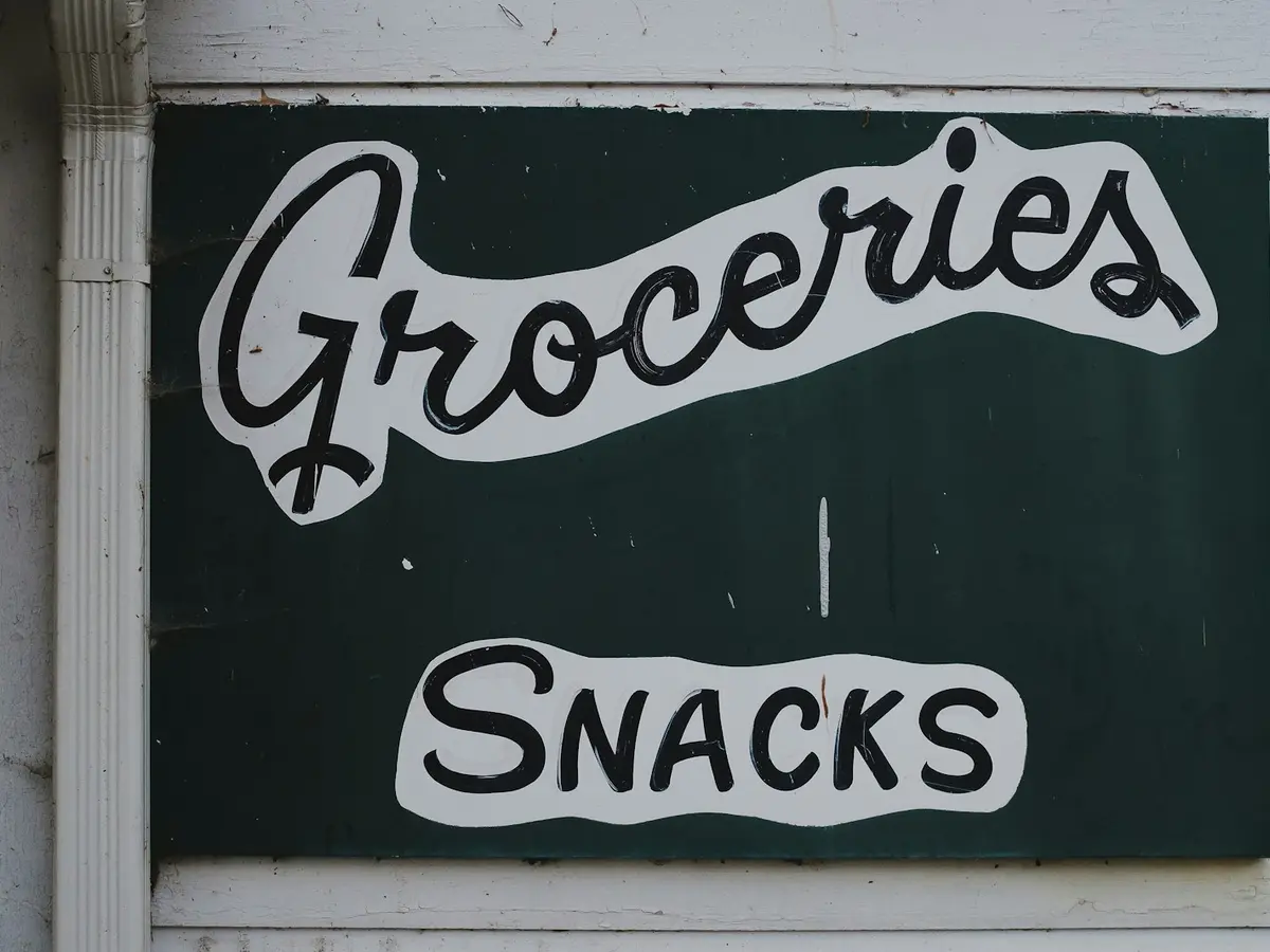 Letreiro comercial pintado à mão com as palavras Groceries e Snacks